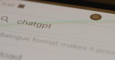 Close-up of a smartphone screen showing a search input field with the term 'chatgpt' typed in, along with a magnifying glass icon to the left and a front-facing camera at the top.